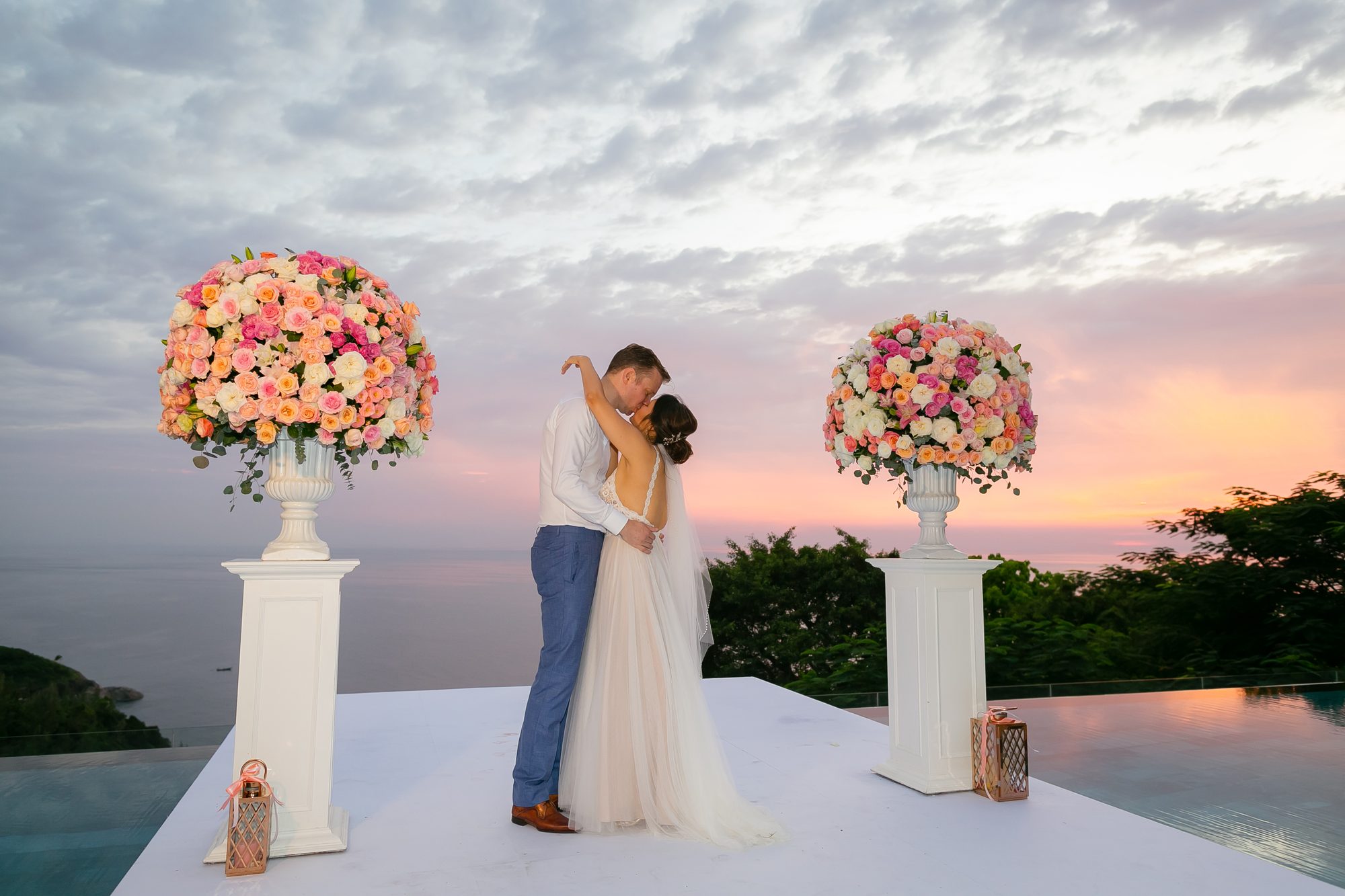 Couple at sunset between tall ivory floral pillars at Villa Aye, Phuket, designed by Wedding Flowers Phuket