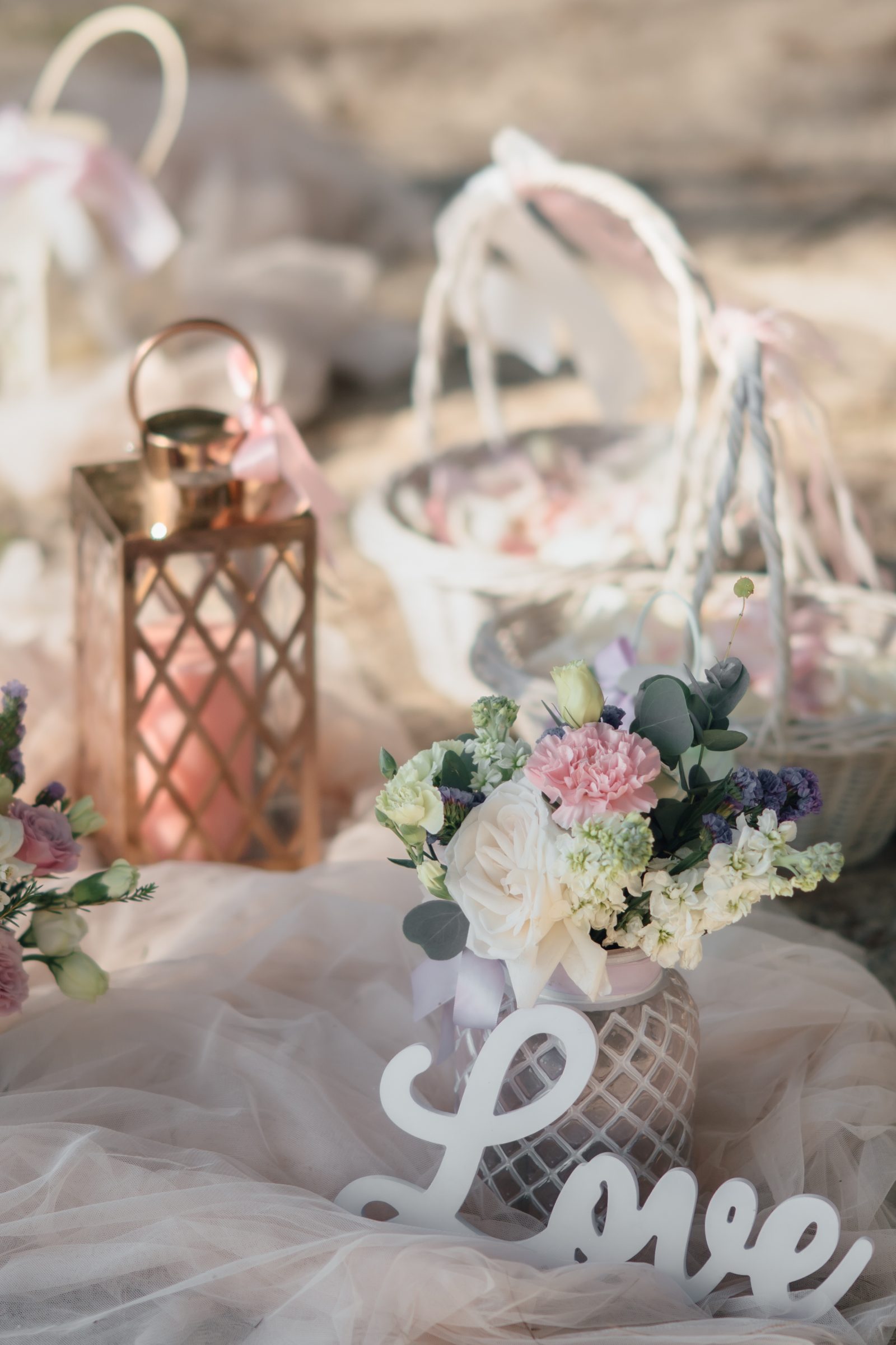 Soft pastel beach floral arrangement and 'Love' sign set on the sand at a Layan Beach elopement, by Wedding Flowers Phuket