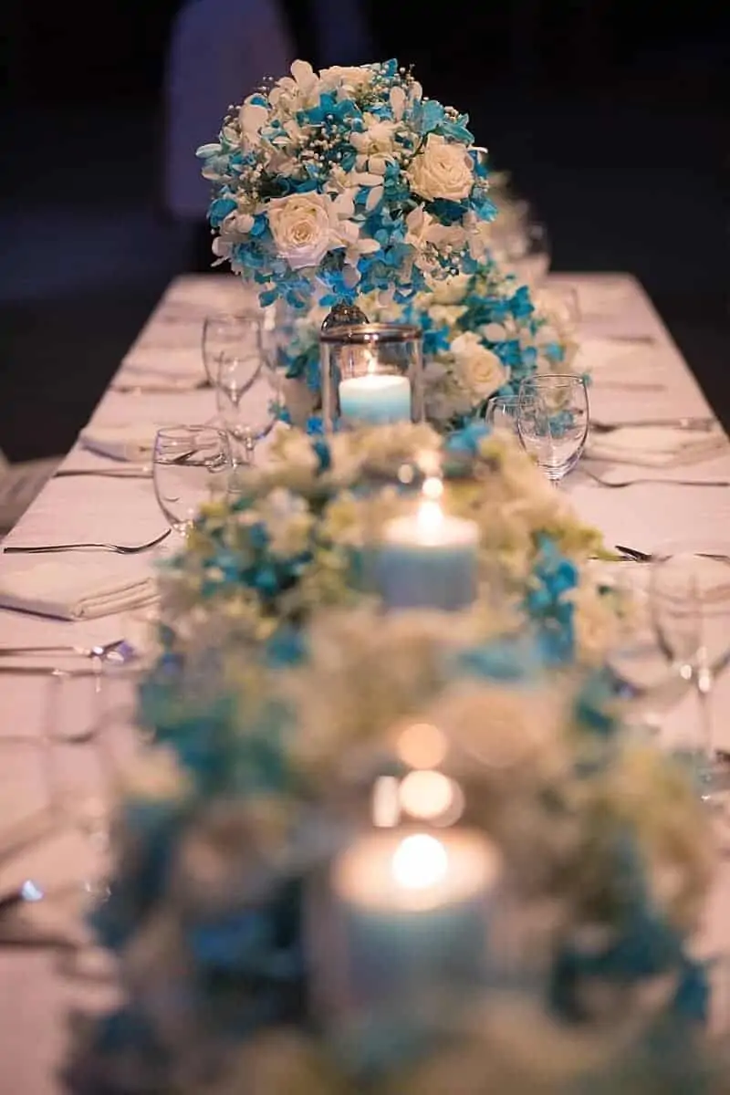 Long-table reception tablescape with low centrepieces and candles at a Phuket wedding by Wedding Flowers Phuket