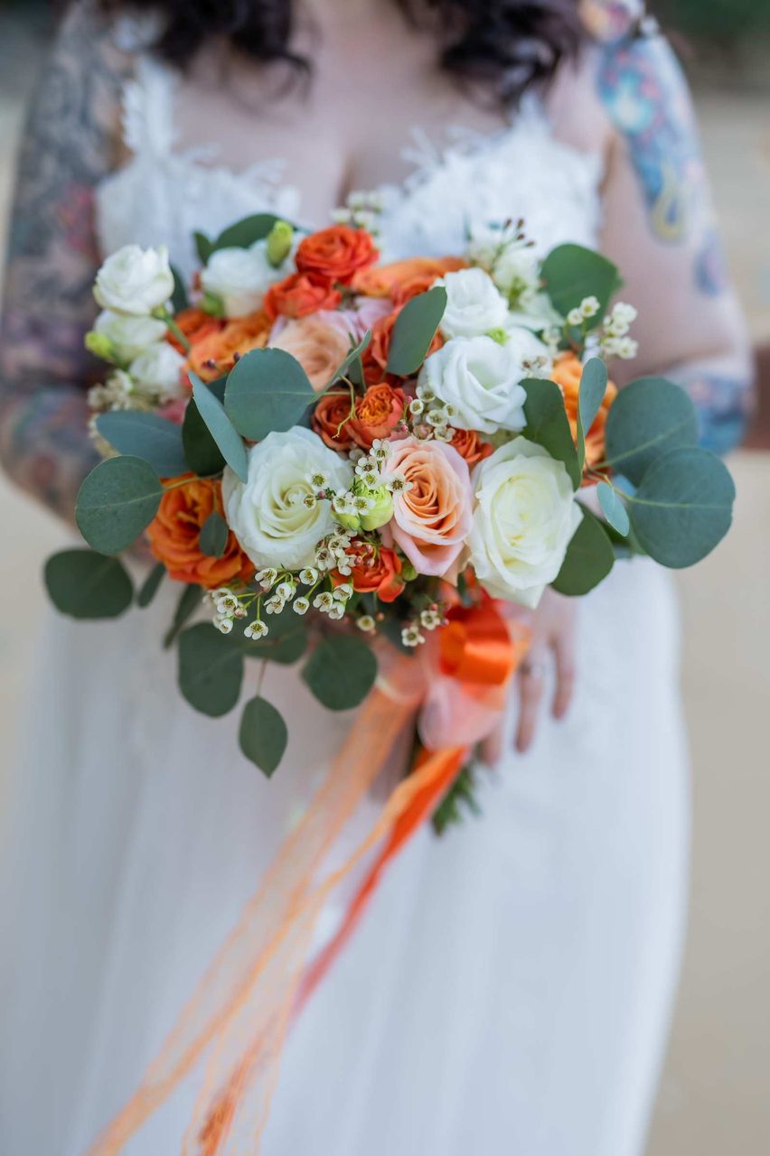 Coral and ivory bridal bouquet on the sand at a Hua Beach wedding, designed by Wedding Flowers Phuket