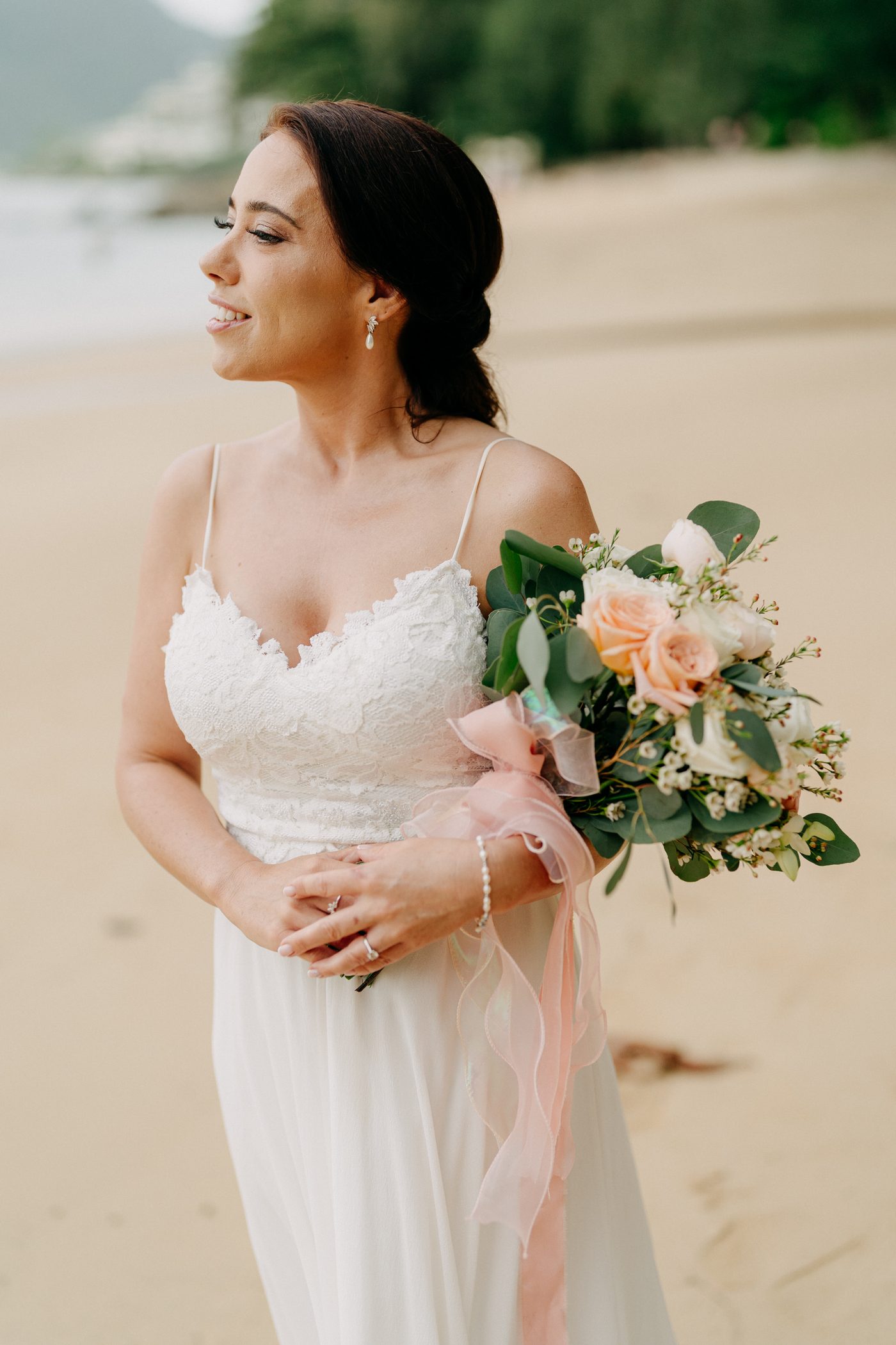 Bride on Hua Beach holding a soft ivory and blush bridal bouquet at golden hour, by Wedding Flowers Phuket