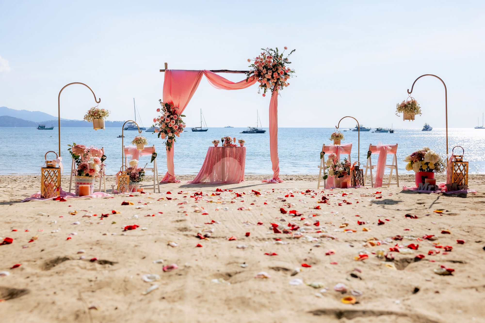 Layan Beach ceremony with sweeping coral and ivory floral pillars overlooking the Andaman sea, designed by Wedding Flowers Phuket