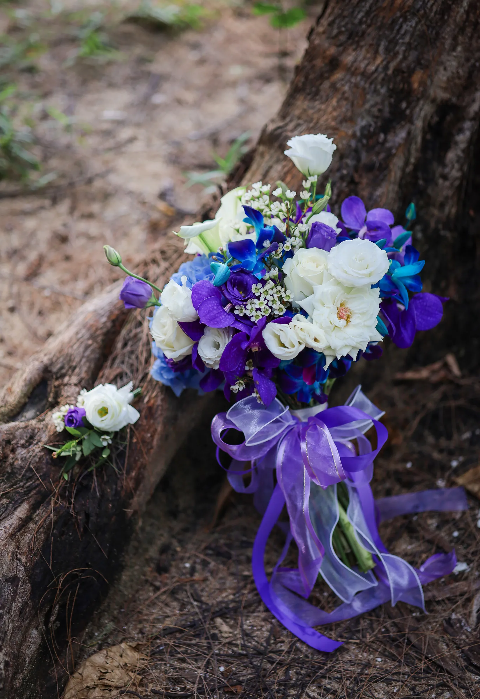 Bridesmaid holding a vivid mixed bouquet — red roses, yellow daisies, blue delphinium and orchid — by Wedding Flowers Phuket